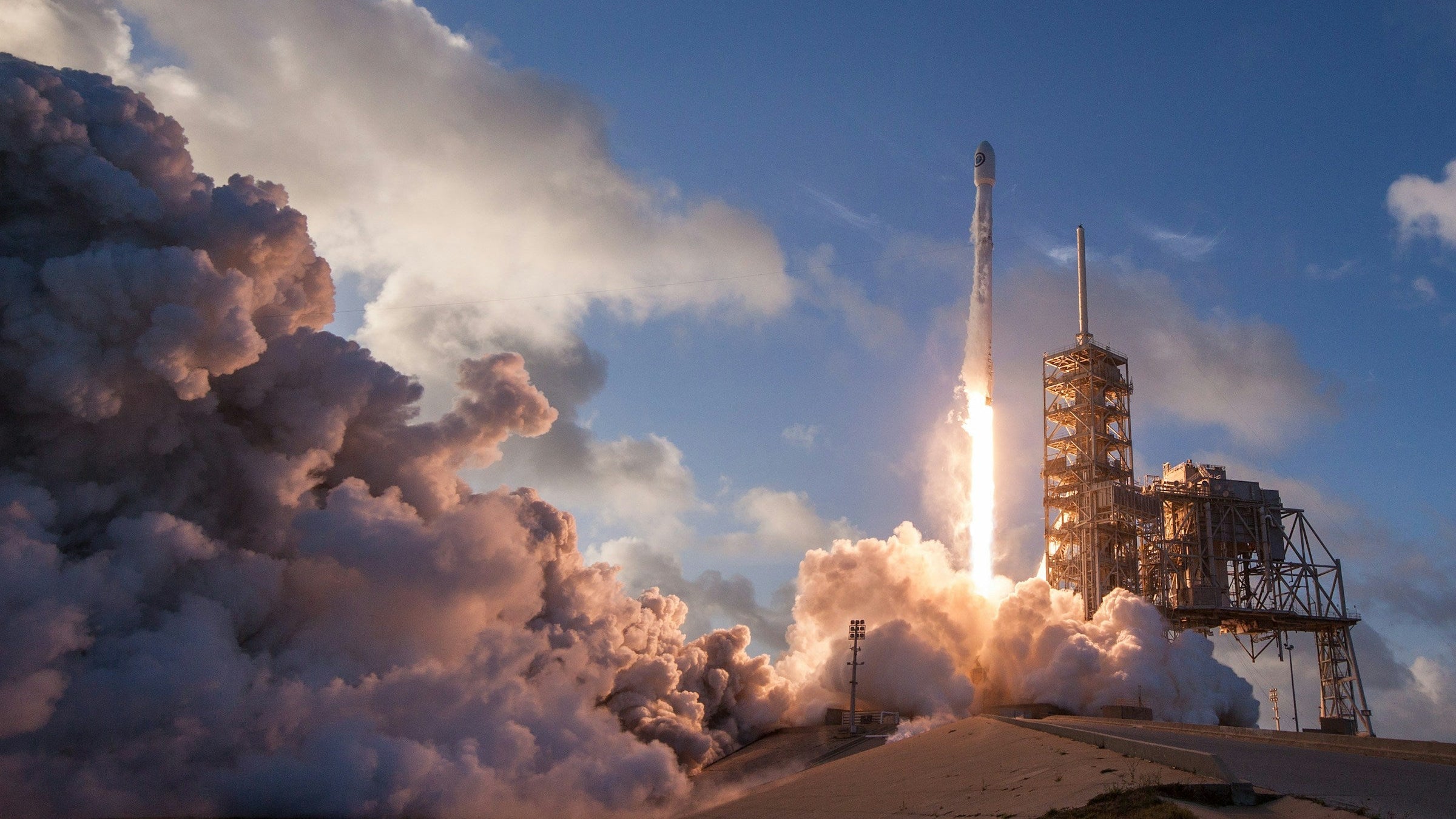 Rocket launching from a launch pad with billowing smoke clouds